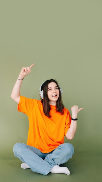 Retrato de una mujer alegre con auriculares que expresa entusiasmo y aprobación mientras señala bot