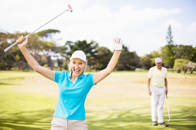 Retrato de mujer alegre golfista con los brazos alzados