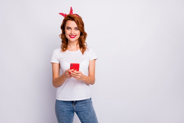 Retrato de mujer alegre positiva que usa el teléfono inteligente quiere seguir, compartir, publicar, reenviar, chatear con amigos en el tiempo libre de verano, usar un traje de buen aspecto aislado sobre una pared de color blanco