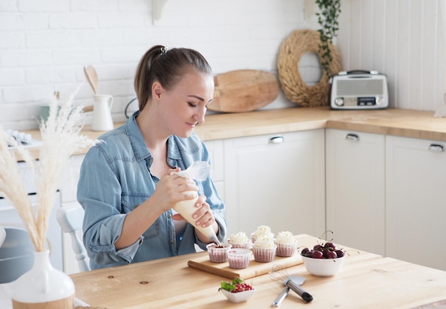 Retrato de una mujer amable y sonriente que hace un cupcake con crema Imagen interior