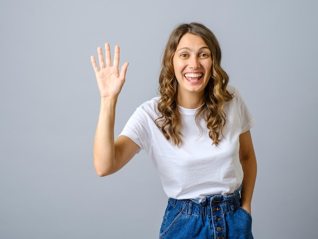 Retrato de una mujer amigable agitando la mano para saludarlo con un gesto de saludo