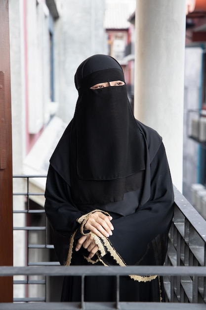 Retrato de una mujer árabe mirando al aire libre mientras se cubre la cara con un velo de niqab tradicional máscara facial islámica concepto de distanciamiento social en la cultura musulmana