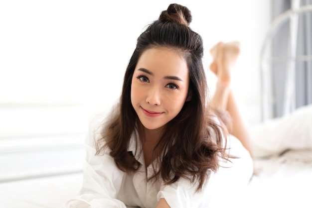 Retrato de mujer asiática disfrutar y relajarse en la cama