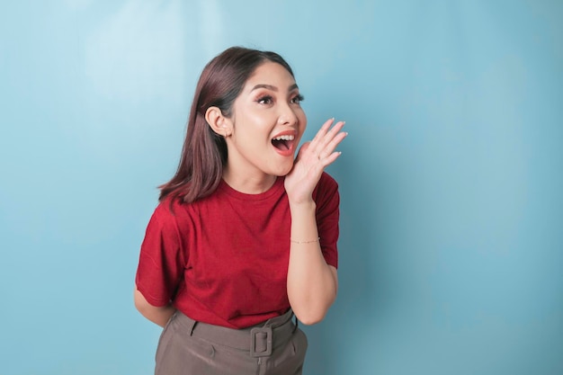 Un retrato de una mujer asiática emocionada que usa una camiseta de lectura gritando aislada por un fondo azul