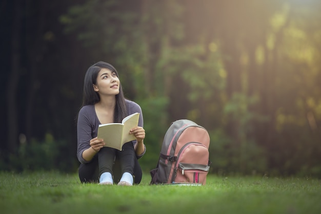 Retrato de mujer asiática encantadora feliz leyendo un libro al aire libre