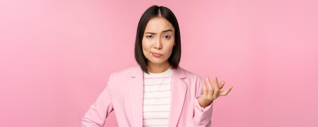 Retrato de una mujer asiática enojada con traje que aprieta los puños y se ve furiosa indignada por algo de mala reputación