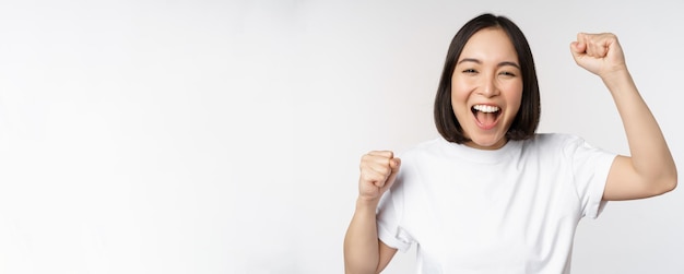 Retrato de mujer asiática entusiasta ganando celebrando y triunfando levantando las manos para lograr goa