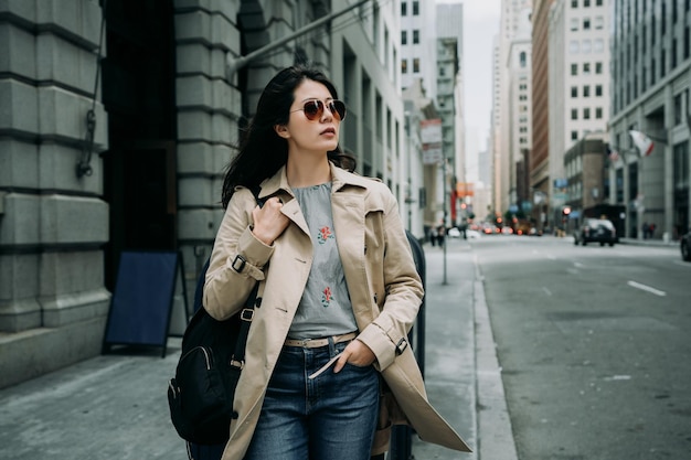 retrato de mujer asiática feliz sonriente con estilo caminando en la calle san francisco usa. atractivo viajero de moda de verano con gafas de sol caminando en una concurrida zona de negocios en la ciudad urbana en un día nublado