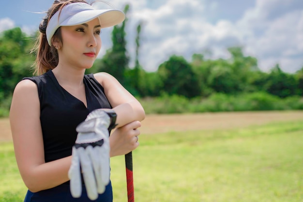 Retrato de mujer asiática golfista sosteniendo madera de golf en el club de campoConcepto de mujer feliz