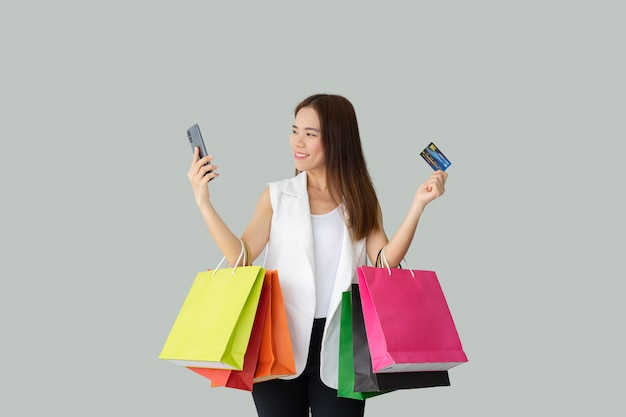 Retrato de mujer asiática hermosa sonriente sosteniendo bolsas de compra con tarjeta de crédito