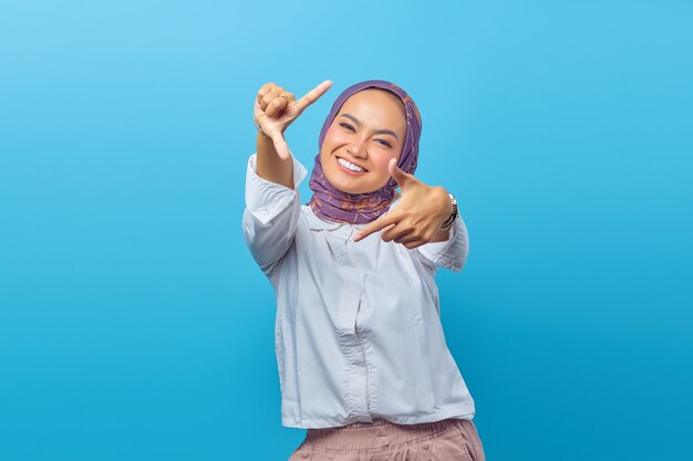 Retrato de mujer asiática joven sonriente mirando a la cámara con las manos haciendo selfie