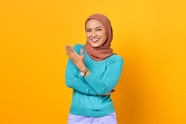 Retrato de mujer asiática joven sonriente que muestra el espacio de la copia en la palma aislada sobre fondo amarillo