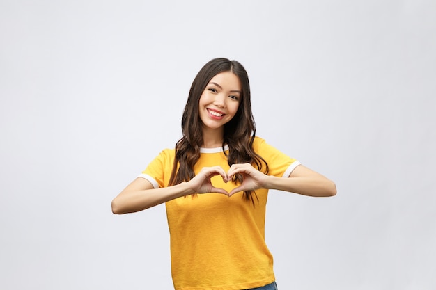 Retrato de una mujer asiática joven sonriente que muestra el gesto del corazón