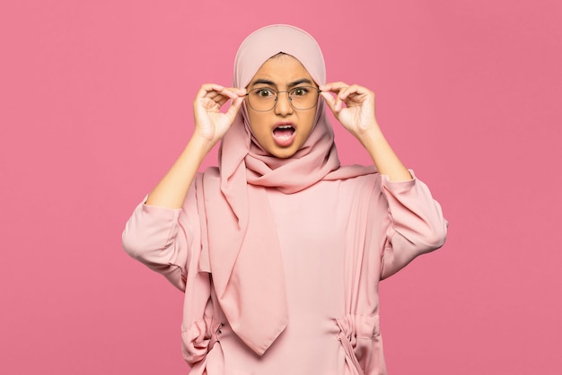 Retrato de mujer asiática joven sorprendida sosteniendo gafas y mirando a la cámara