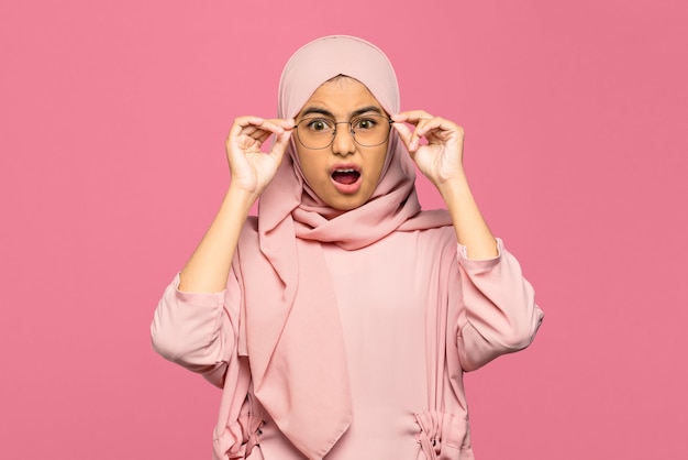 Retrato de mujer asiática joven sorprendida sosteniendo gafas y mirando a la cámara