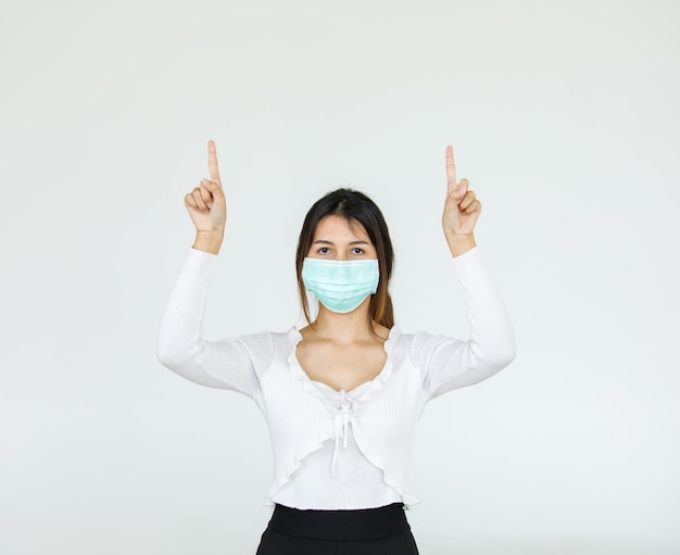 Retrato de mujer asiática con una máscara facial plantea, señalando publicidad sobre fondo blanco, espacio de copia en blanco con recorte de fondo blanco aislado.