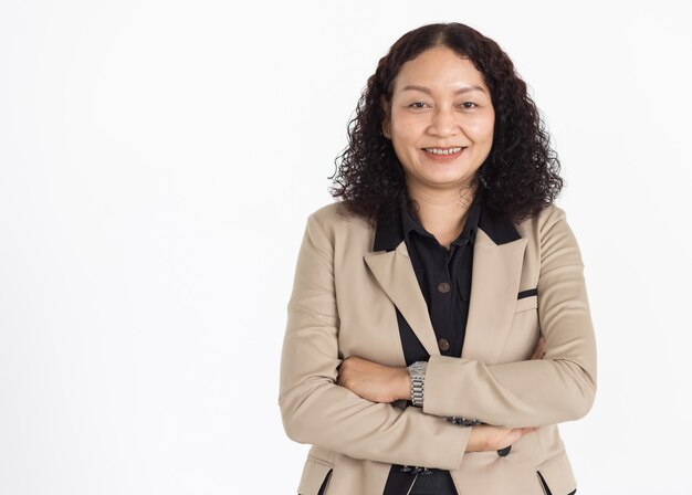 Retrato de mujer asiática de mediana edad con cabello negro rizado con camisa negra y chaqueta beige mirando cuidadosamente sonriendo con confianza aislada.