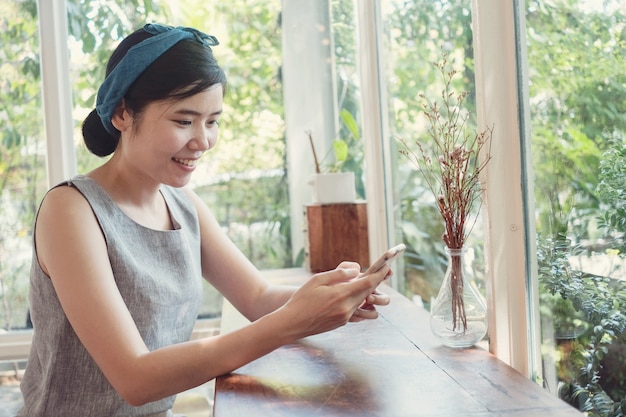 Retrato de una mujer asiática de mediana edad saludable de 40 años que hace videollamadas con teléfono inteligente en casa, usando la aplicación en línea para reuniones con zoom, distanciamiento social, trabajo desde casa, concepto de trabajo remoto