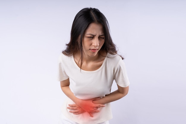 Retrato de mujer asiática que sufre de dolor de estómago aislado sobre fondo blanco.