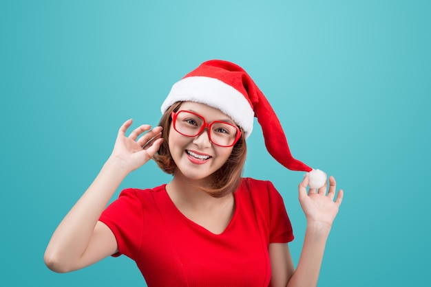 Retrato de mujer asiática sonriente con gorro de Papá Noel de Navidad aislado sobre fondo azul.