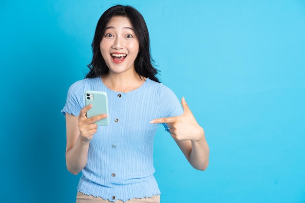 Retrato de mujer asiática sonriente posando sobre fondo azul.