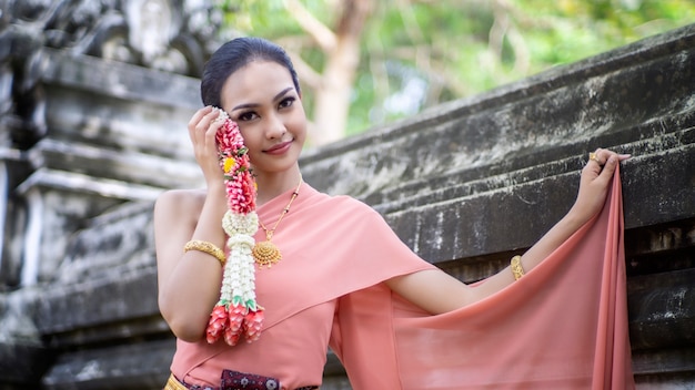 Retrato de una mujer asiática en tailandesa Bailarina tradicional La ropa está de pie contra la antigua estatua de Buda. Parque histórico de Ayuttaya, Tailandia Asia.