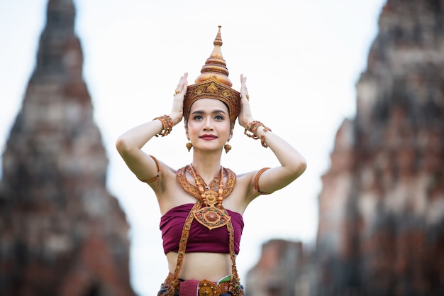 Retrato de una mujer asiática en tailandesa Bailarina tradicional La ropa está de pie contra la antigua estatua de Buda. Parque histórico de Ayuttaya, Tailandia Asia.