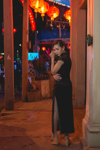 Retrato de una mujer asiática vestida de negro en la pasarela en la escena nocturna del centro de la ciudad cierra el estilo callejero de una chica