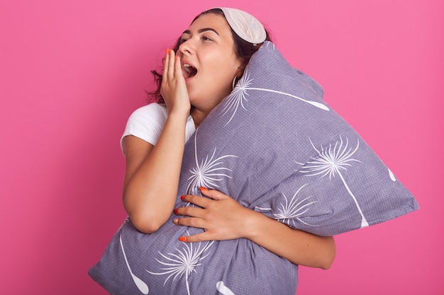 Retrato de mujer atractiva bostezando como tiene expresión soñolienta