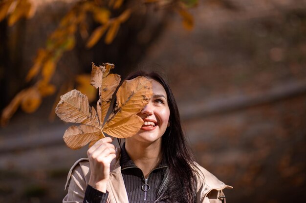 Retrato de mujer atractiva y elegante en la temporada de otoño que posa con hoja amarilla