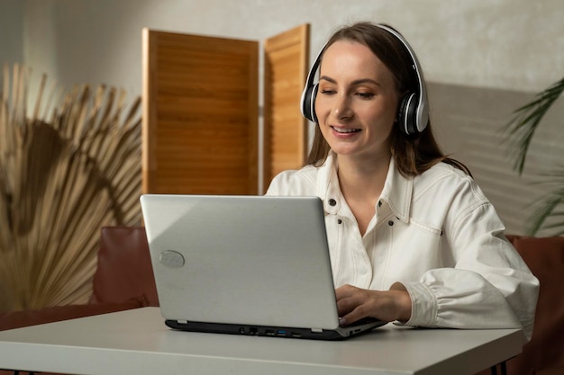 Retrato de una mujer con auriculares jugando videojuegos en una computadora portátil