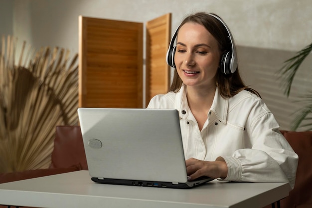 Foto retrato de una mujer con auriculares jugando videojuegos en una computadora portátil