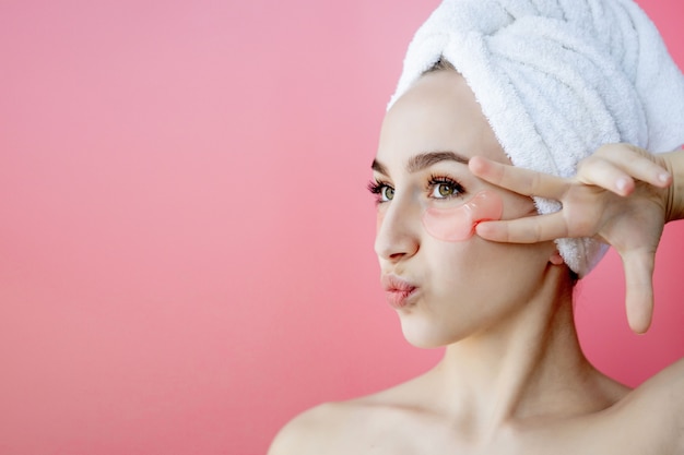 Retrato de mujer de belleza con parches en el fondo de color rosa. Rostro de belleza de mujer con máscara debajo de los ojos. Cuidado de la piel, concepto de producto cosmético con espacio de copia