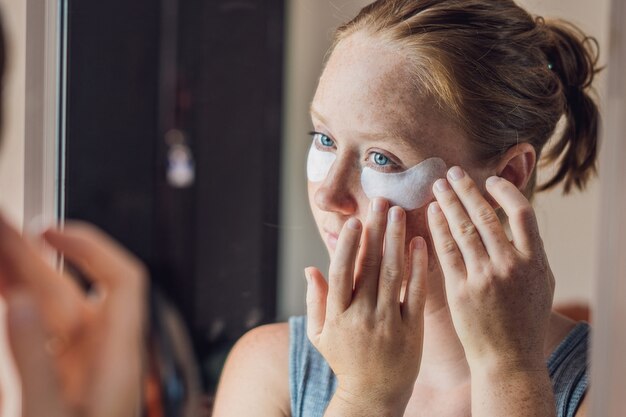 Retrato de mujer de belleza pelirroja con parches en los ojos que muestran un efecto de piel perfecta. Chica de spa.