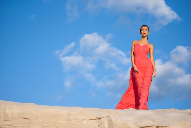 Retrato de una mujer de belleza vestida de rojo en el desierto