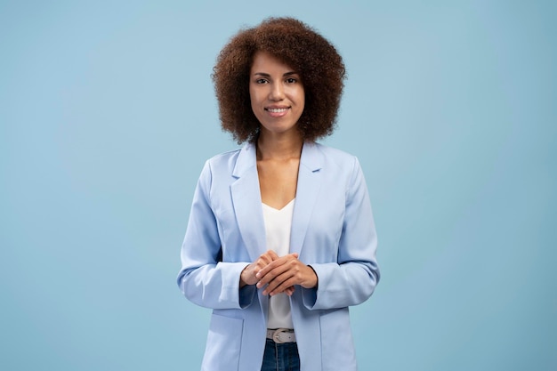 Retrato de una mujer bonita afroamericana segura de sí misma sonriendo mirando a la cámara con fondo azul