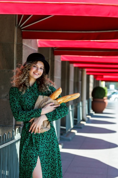 Retrato de mujer bonita con baguette en manos en la calle. Mujer vestida a la francesa