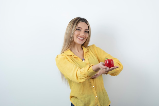 Foto retrato de mujer bonita en camisa amarilla que ofrece pimientos rojos