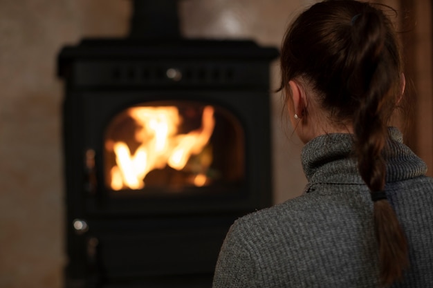 Retrato de mujer bonita caucásica pasar tiempo por la noche en casa junto a la chimenea