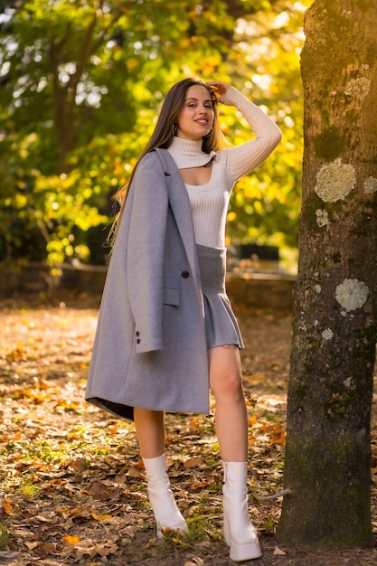 Retrato de una mujer bonita disfrutando del otoño en un parque al atardecer junto a un árbol