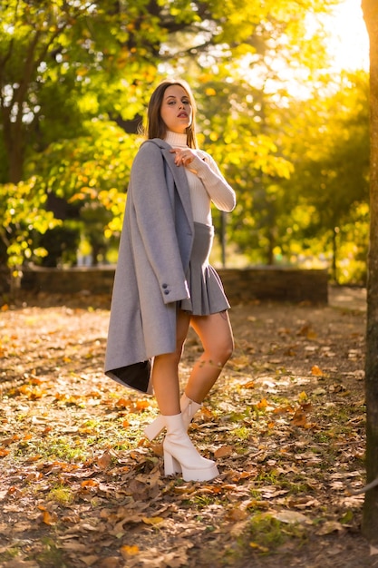 Retrato de una mujer bonita disfrutando del otoño en un parque al atardecer traje otoñal