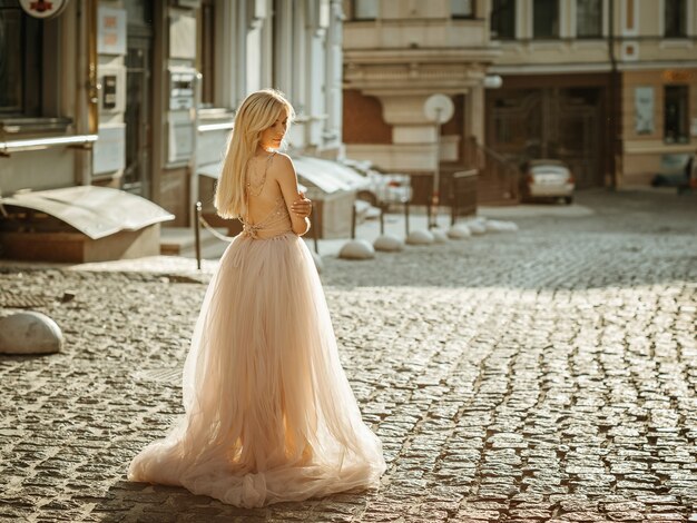 Retrato de una mujer bonita elegante con vestido de novia gris y posando en la calle