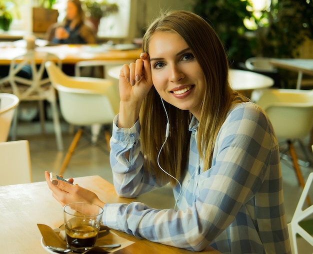 Retrato de una mujer bonita escuchando música y sosteniendo un teléfono móvil