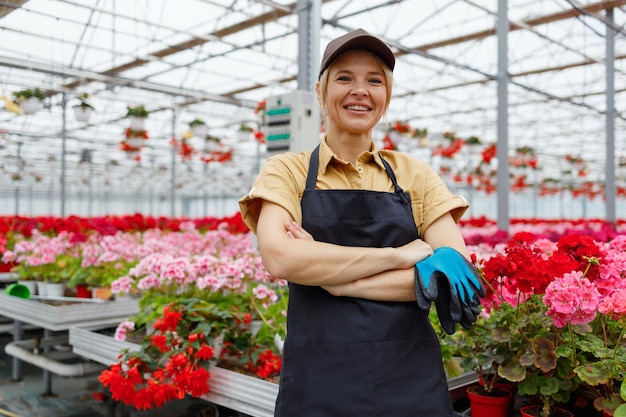 Retrato de mujer bonita floristería vestida con uniforme de trabajo en el invernadero