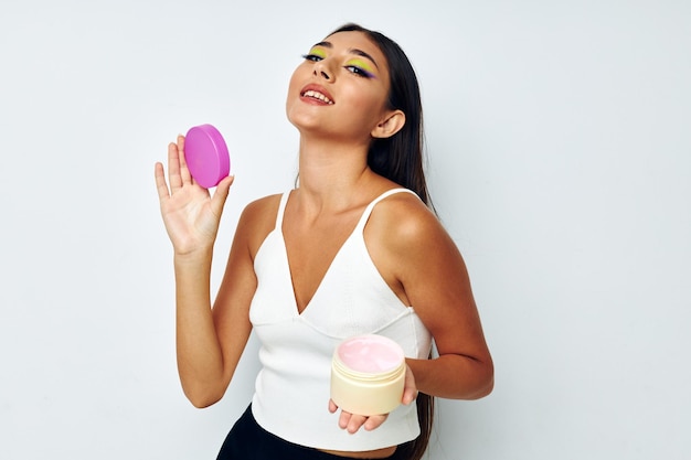 Retrato de mujer bonita en un frasco de jersey blanco con fondo claro de cosméticos inalterado