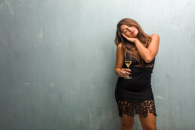 Retrato de una mujer bonita joven con un vestido contra una pared cansada y con mucho sueño