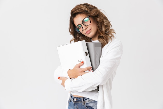 Retrato de mujer bonita secretaria con anteojos sonriendo y sosteniendo una carpeta de papel, mientras está aislado