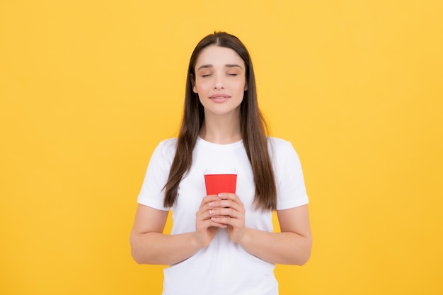 Retrato de una mujer bonita sosteniendo una taza de café para llevar aislada sobre fondo amarillo