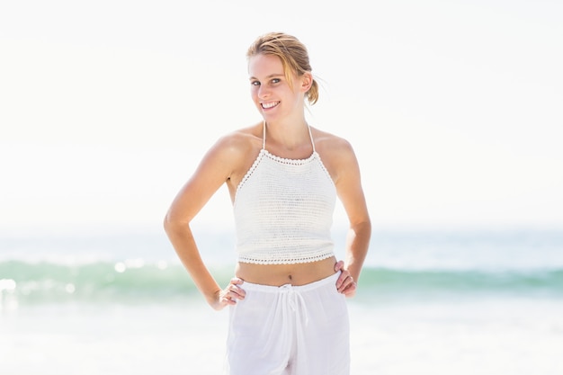 Retrato de mujer bonita en traje blanco de pie en la playa