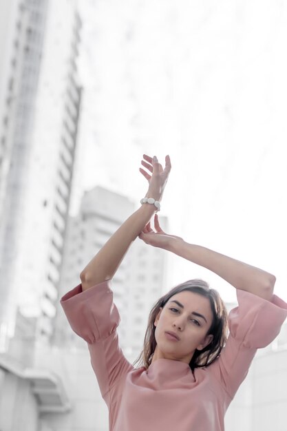 Foto retrato de una mujer con los brazos levantados contra los edificios